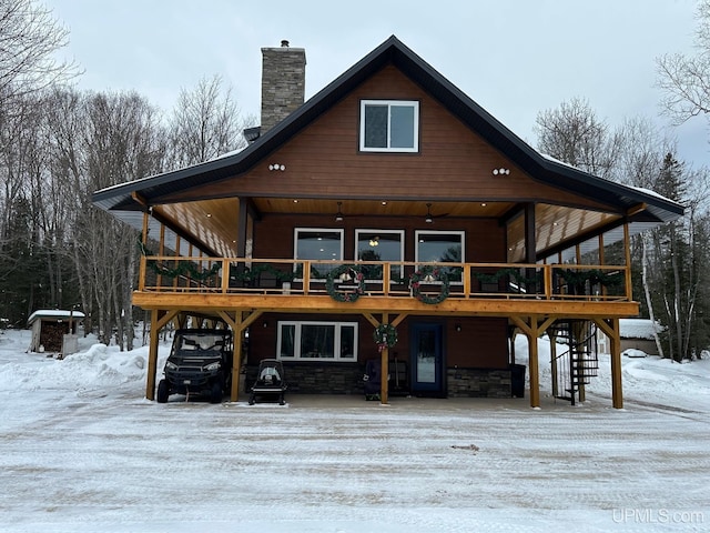 snow covered back of property with a wooden deck