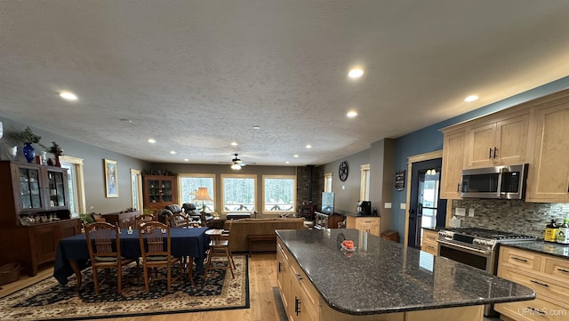 kitchen featuring light wood-type flooring, a center island, a textured ceiling, and appliances with stainless steel finishes