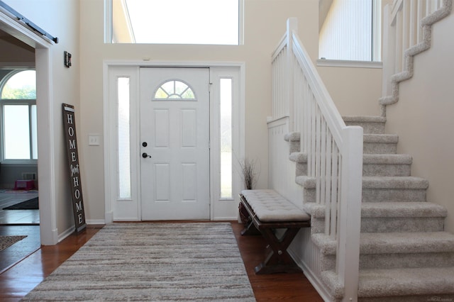 entrance foyer with dark hardwood / wood-style floors, a barn door, and a high ceiling