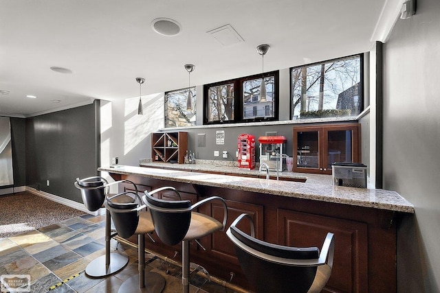 bar with pendant lighting, ornamental molding, and light stone countertops