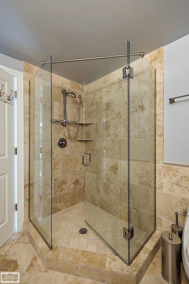 bathroom featuring tile walls and a shower with door