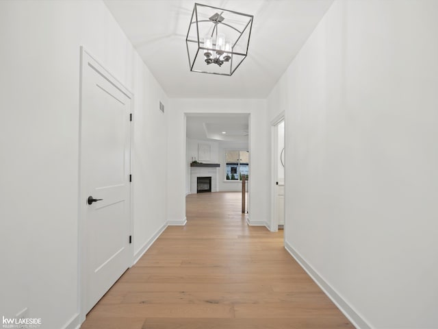 corridor featuring an inviting chandelier and light wood-type flooring