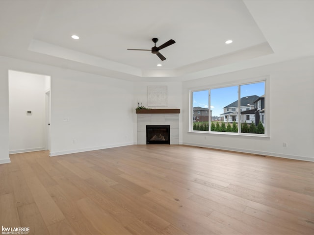 unfurnished living room with light wood-type flooring and a tray ceiling