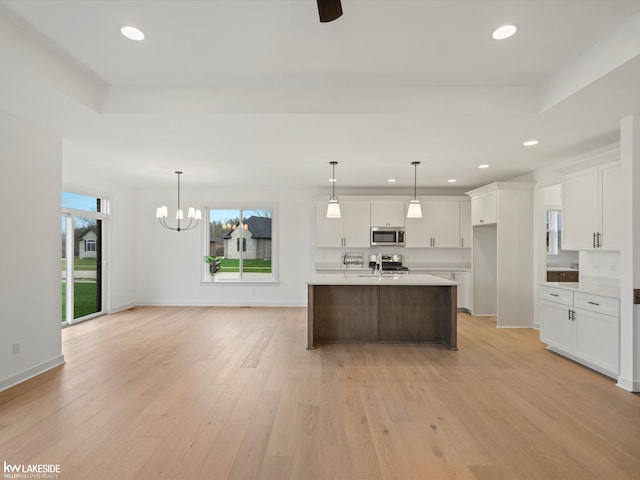 kitchen featuring white cabinetry, stainless steel appliances, decorative light fixtures, and light wood-type flooring