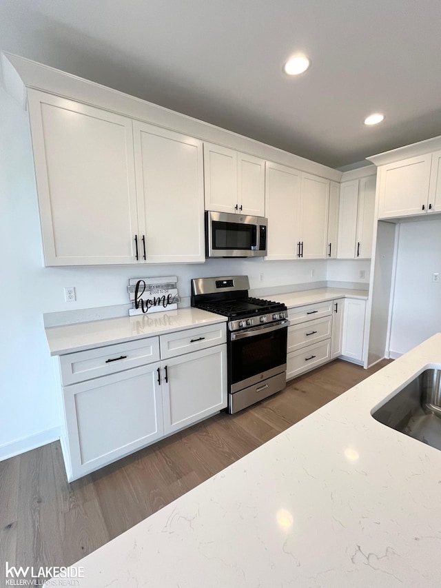 kitchen with sink, hardwood / wood-style flooring, white cabinets, and appliances with stainless steel finishes