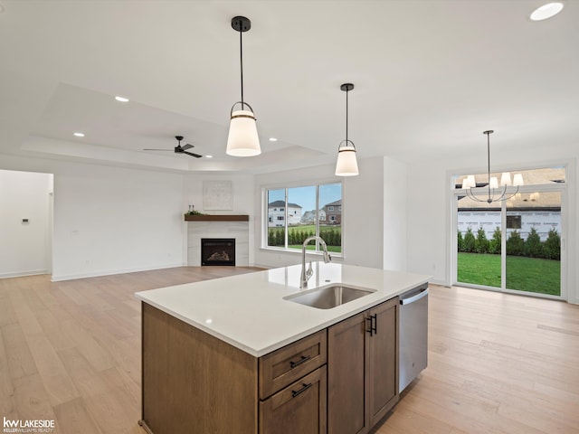 kitchen with decorative light fixtures, dishwasher, sink, and a raised ceiling