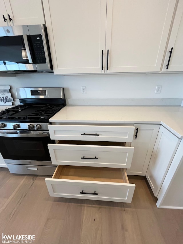 kitchen featuring stainless steel appliances, hardwood / wood-style floors, and white cabinets