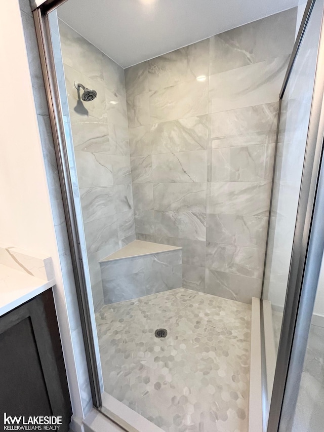 bathroom with tiled shower and vanity