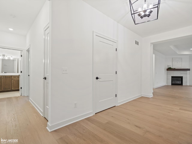 hall with light hardwood / wood-style flooring and a chandelier