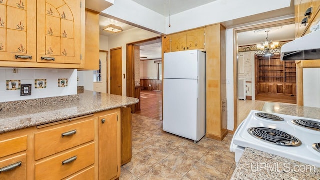 kitchen with light stone countertops, a notable chandelier, and white appliances