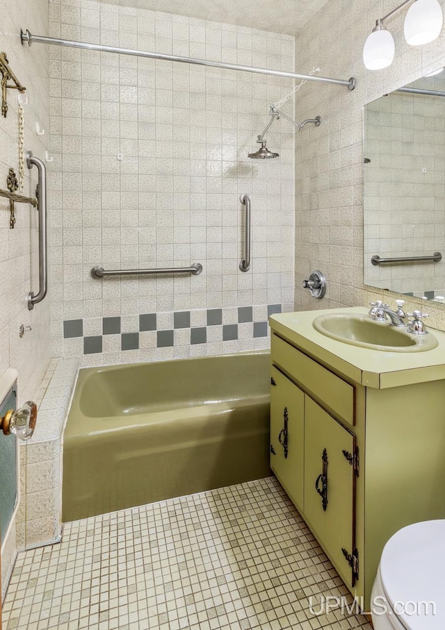 full bathroom featuring vanity, tile patterned flooring, toilet, and tiled shower / bath