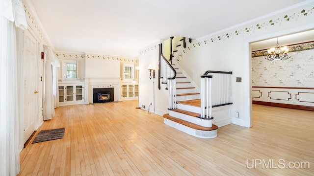 unfurnished living room with an inviting chandelier, wood-type flooring, and ornamental molding