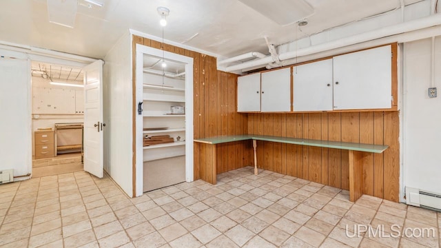 basement featuring a baseboard radiator and wood walls