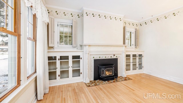 unfurnished living room featuring crown molding, wood-type flooring, and a wood stove