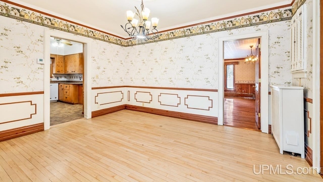 spare room featuring ornamental molding, a chandelier, and light wood-type flooring