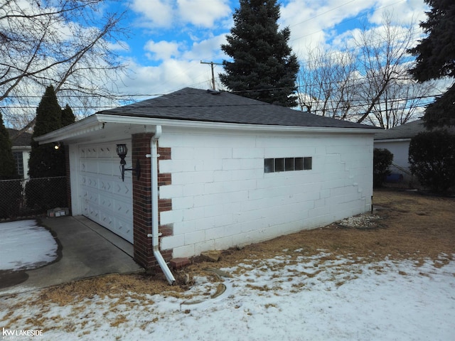 view of snow covered exterior featuring a garage and an outdoor structure