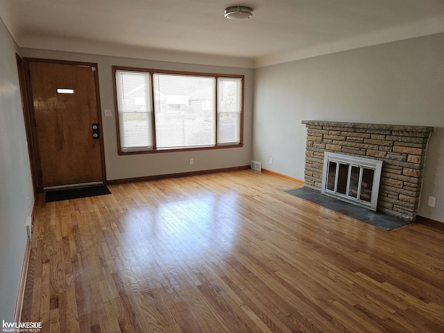 unfurnished living room with a stone fireplace and light hardwood / wood-style floors