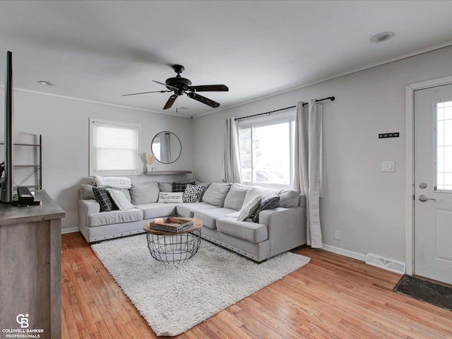 living room with ceiling fan, ornamental molding, and light wood-type flooring