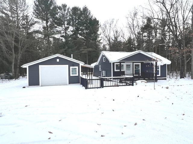 snow covered house featuring an outbuilding and a garage