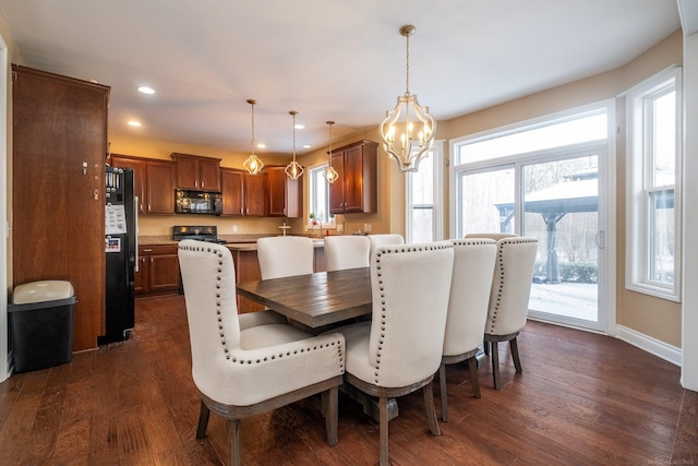 dining area with sink, dark wood-type flooring, and a chandelier