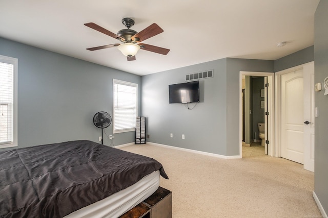 bedroom featuring light colored carpet, ceiling fan, and ensuite bathroom