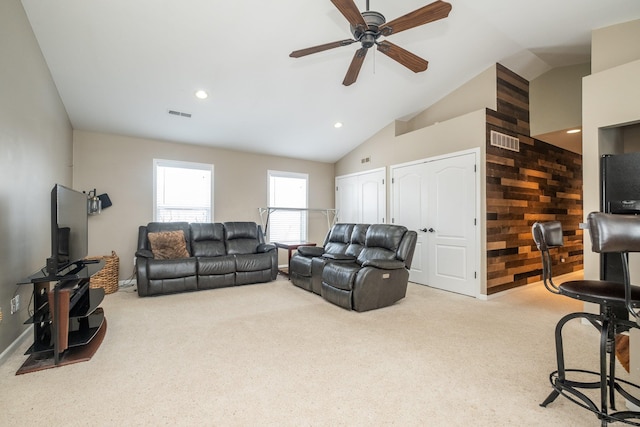 living room with ceiling fan, light colored carpet, wooden walls, and high vaulted ceiling