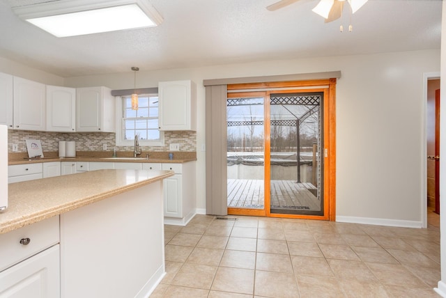 kitchen with pendant lighting, sink, decorative backsplash, and white cabinets