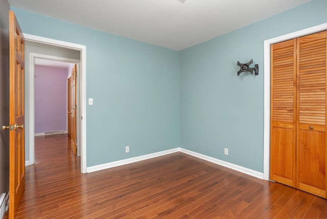 unfurnished bedroom with dark wood-type flooring and a closet