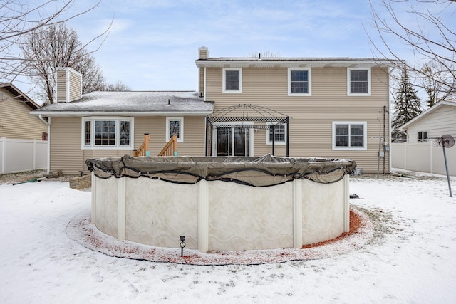 snow covered back of property featuring a gazebo and a covered pool