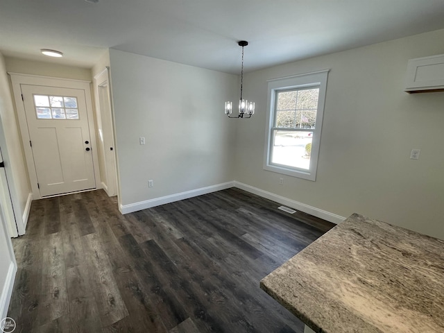 unfurnished dining area featuring dark wood-type flooring and a chandelier
