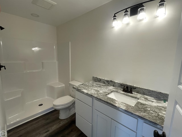 bathroom featuring wood-type flooring, toilet, vanity, and a shower