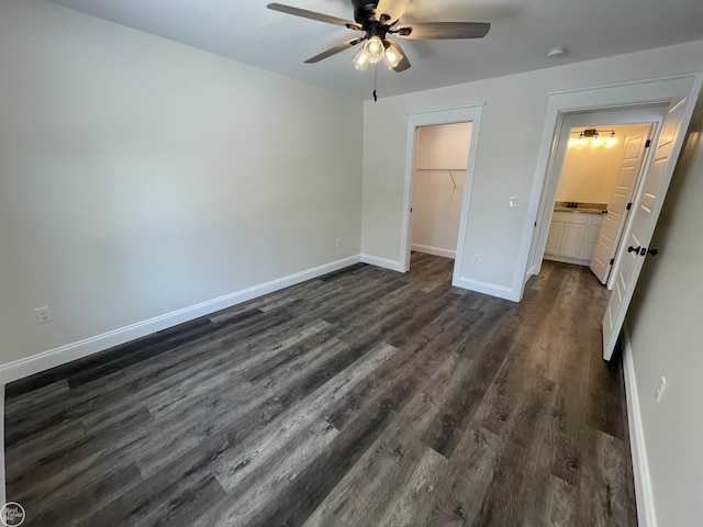 unfurnished bedroom featuring dark wood-type flooring, ceiling fan, a spacious closet, and a closet