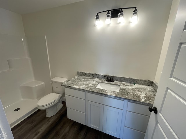 bathroom featuring hardwood / wood-style flooring, vanity, toilet, and walk in shower