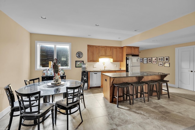 kitchen with sink, a breakfast bar, appliances with stainless steel finishes, a kitchen island, and dark stone counters