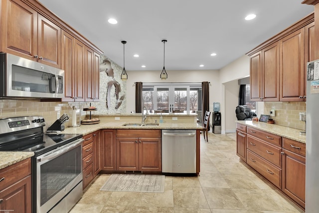 kitchen featuring pendant lighting, sink, kitchen peninsula, stainless steel appliances, and light stone countertops