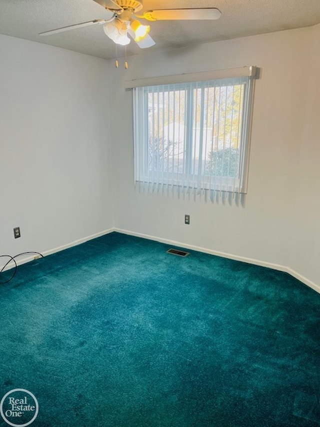 carpeted empty room with ceiling fan and a textured ceiling