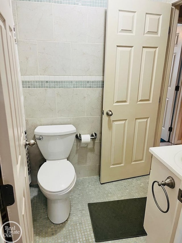 bathroom featuring vanity, tile walls, tile patterned floors, and toilet