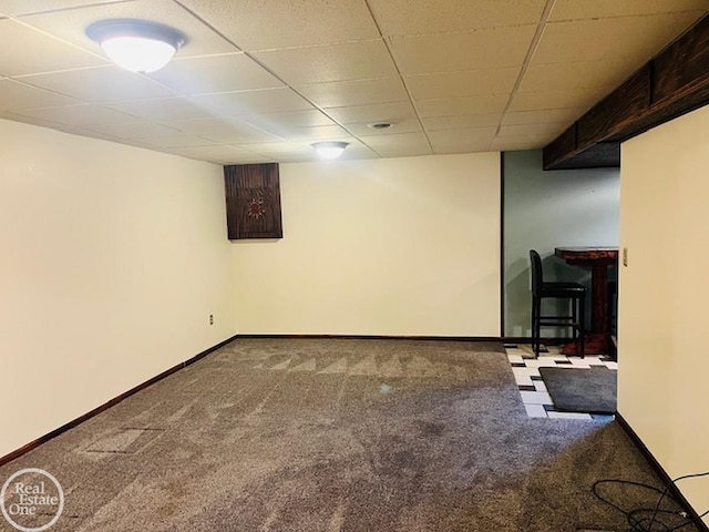 basement featuring a paneled ceiling and carpet flooring