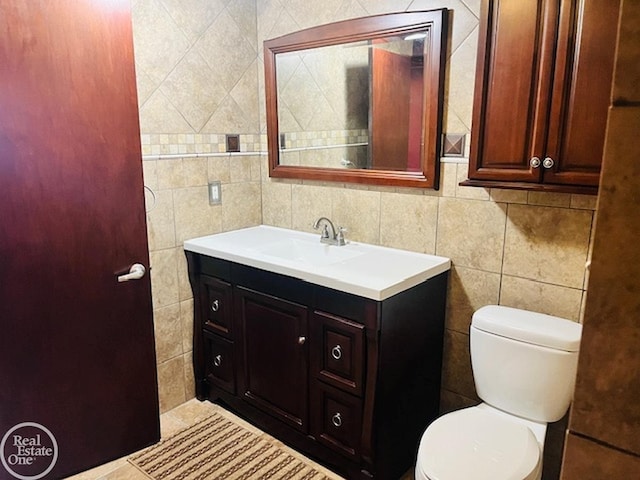 bathroom featuring vanity, toilet, and tile walls