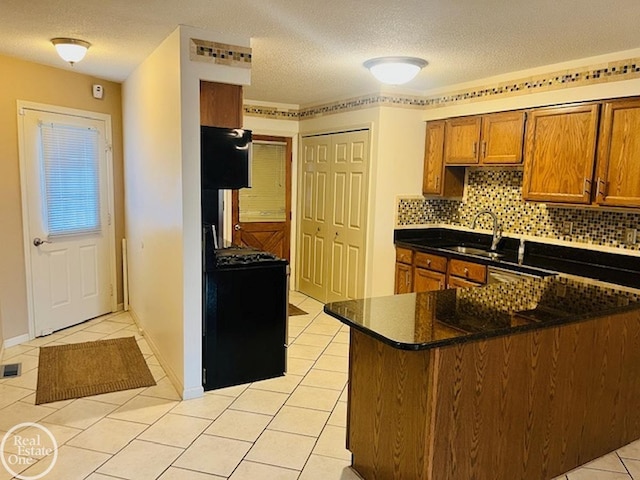 kitchen with light tile patterned floors, sink, a textured ceiling, and backsplash