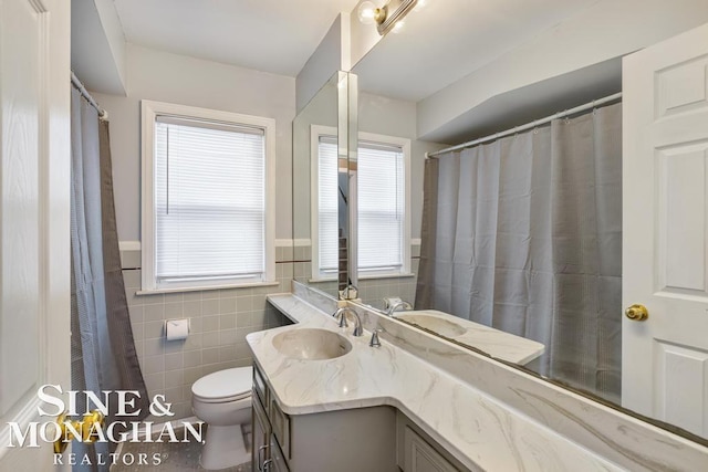 bathroom with tile walls, vanity, and toilet