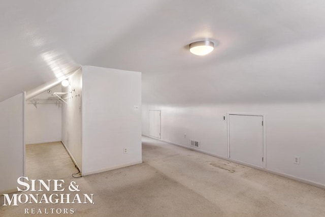 bonus room with light colored carpet and vaulted ceiling