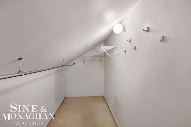 spacious closet with vaulted ceiling and light colored carpet