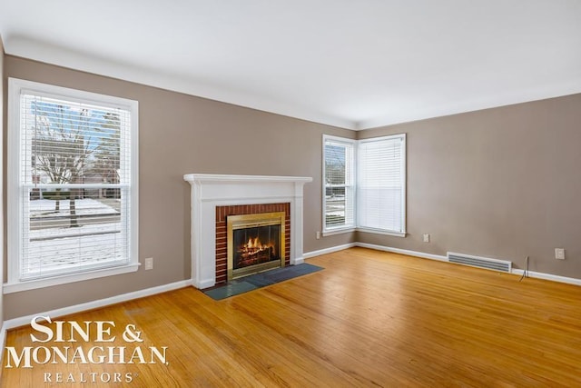 unfurnished living room with hardwood / wood-style flooring, plenty of natural light, and a fireplace