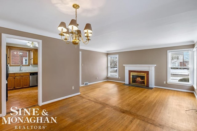 unfurnished living room with a healthy amount of sunlight, sink, a fireplace, and light hardwood / wood-style flooring