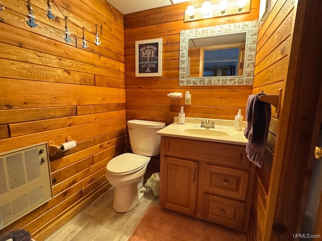 bathroom featuring heating unit, vanity, wooden walls, and toilet