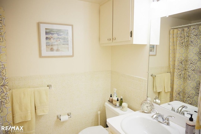 bathroom featuring vanity, toilet, and tile walls