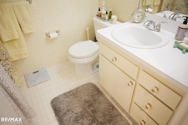 bathroom with vanity, toilet, and tile walls