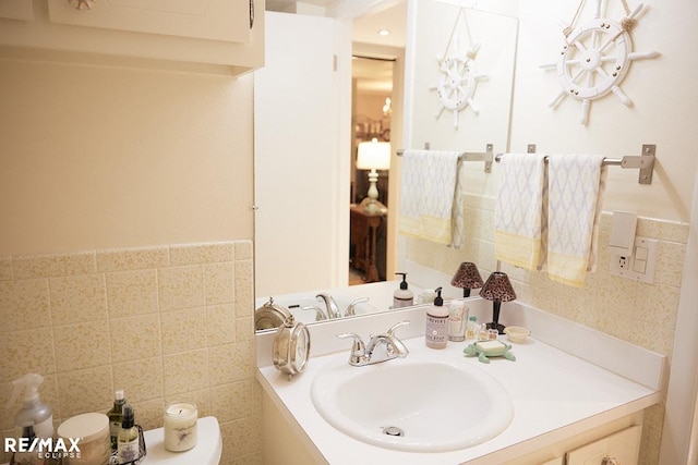 bathroom featuring vanity, tile walls, and toilet