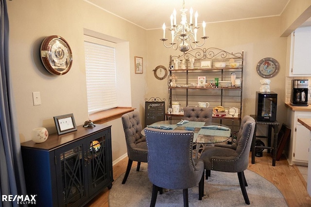 dining area with ornamental molding, light hardwood / wood-style floors, and a notable chandelier